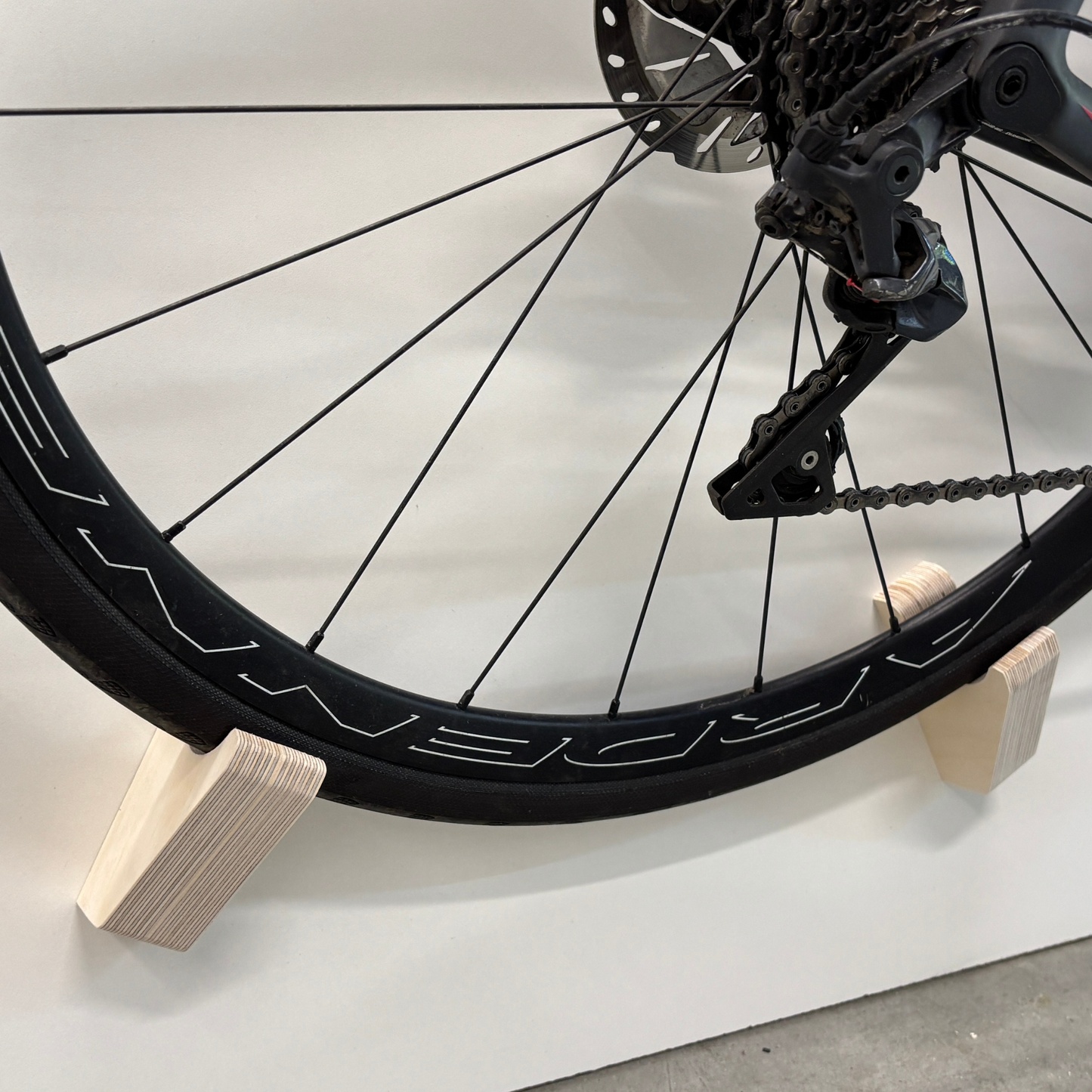 Support vélo mural design – Bois massif ou contreplaqué de merisier, accroche par roues et cadre, angle 15–20°, vis et ancrages inclus